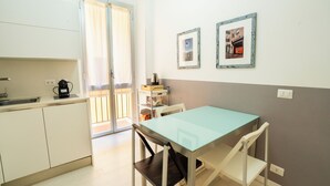 A small kitchen with a table and chairs, a coffee maker, and a door leading to a balcony. - Rome City Center modern loft - special offer (Roma)