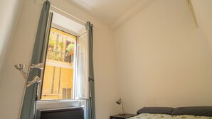 A bedroom with a bed, a nightstand, a lamp, and a window with curtains. - Rome City Center modern loft - special offer (Roma)
