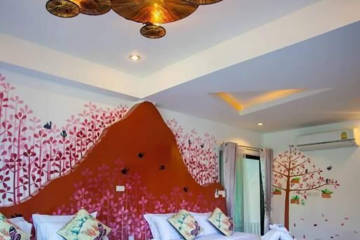 A bedroom with two beds, a decorative ceiling light, and a wall mural.