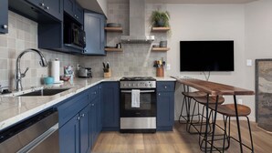 Una cocina moderna con armarios azules, una estufa de acero inoxidable, un microondas y una zona con taburetes de bar.