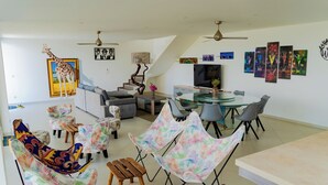 Ein modernes Wohnzimmer mit einer Couch, Sesseln, einem Esstisch und einer Treppe.