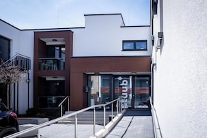 A modern building with a glass entrance, a staircase, and a metal railing.