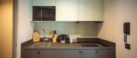 A compact kitchen with a microwave, sink, and cabinets.