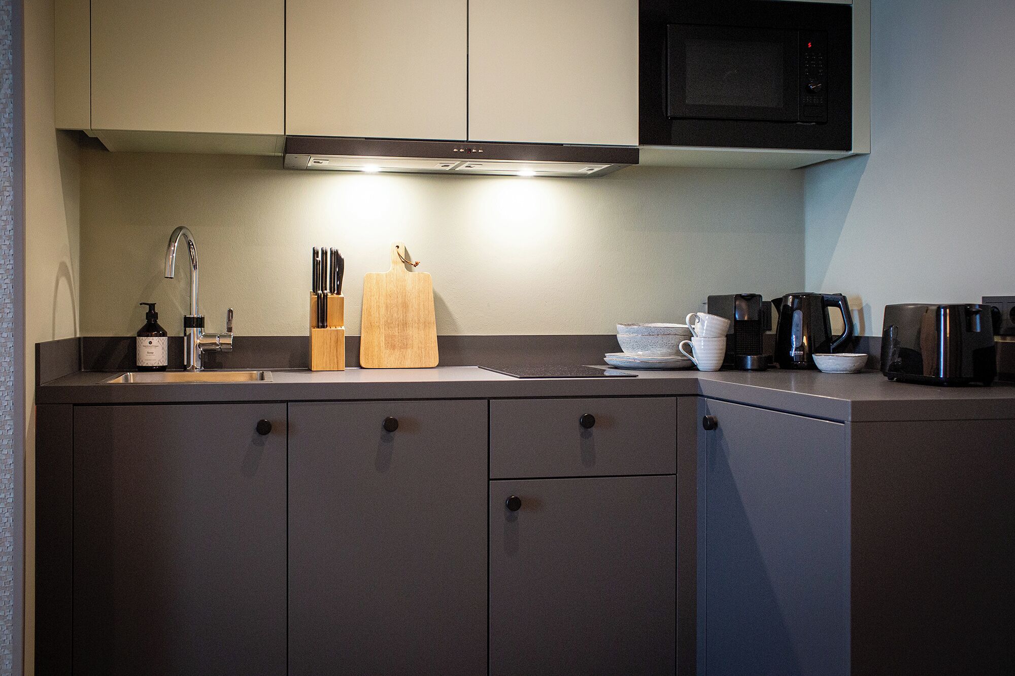 A modern kitchen with a built-in microwave, a coffee maker, and a knife block.