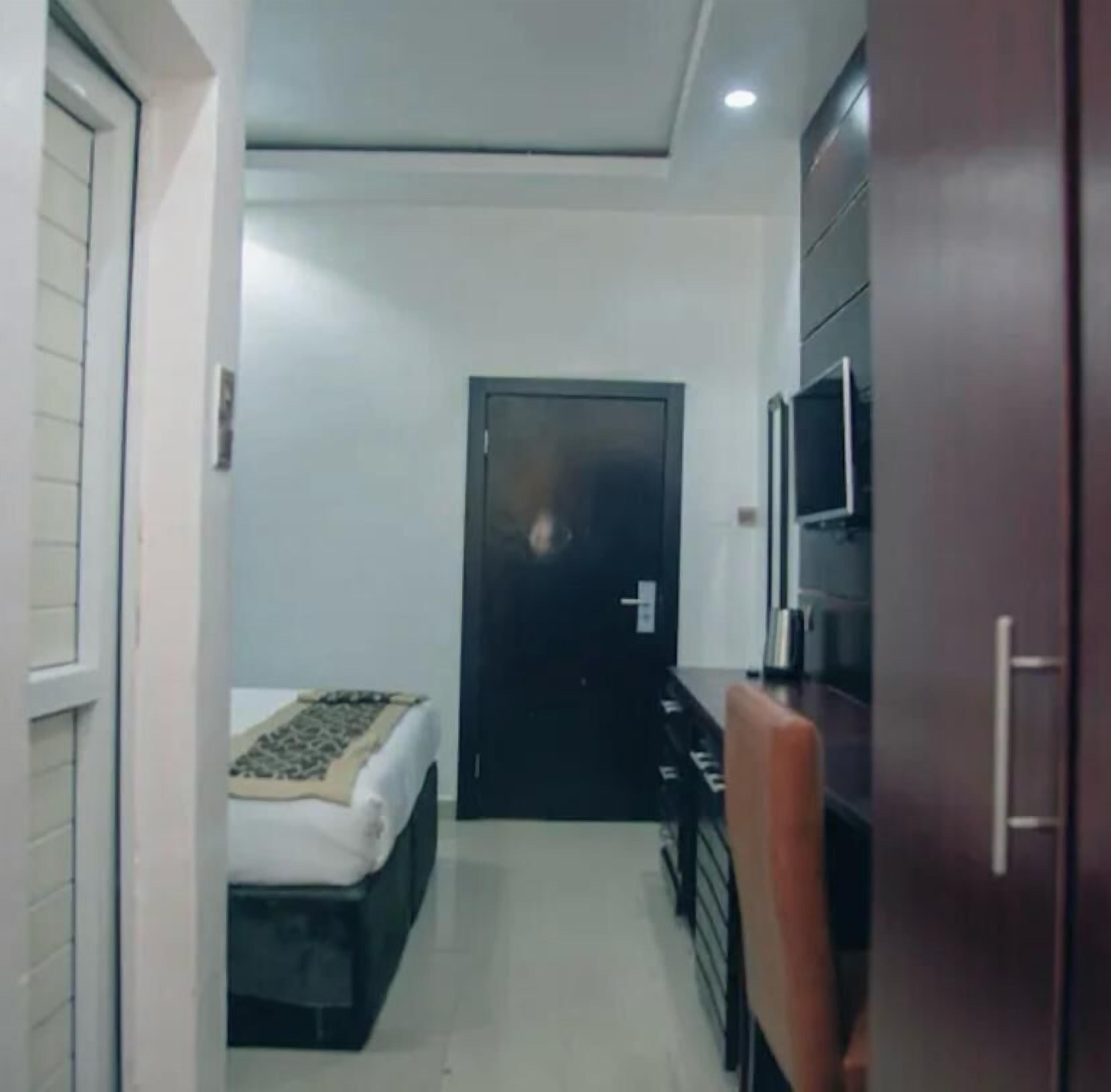 A compact hotel room with a bed, a desk, a chair, and a wardrobe.