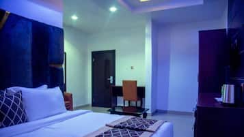 A hotel room with a bed, a desk, and a chair.