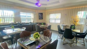 Uma sala de jantar moderna com uma mesa redonda central, rodeada por cadeiras, e um lustre decorativo.
