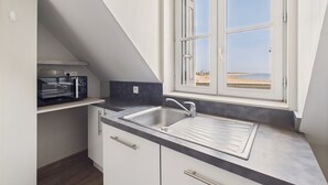Una cocina con horno empotrado, pileta y ventana con vista a la playa.