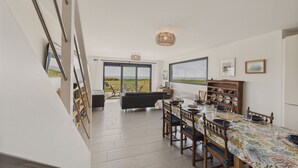 Uma sala de jantar com mesa posta para seis pessoas, vista para o exterior e uma grande janela.
