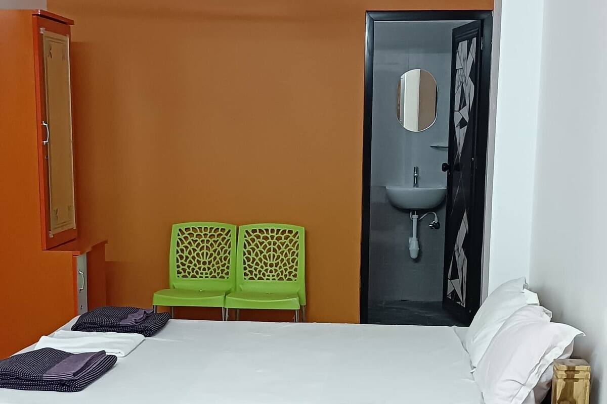 Ein Schlafzimmer mit Bett, Deckenventilator, Klimaanlage, Kleiderschrank und einem Badezimmer mit Waschbecken und Spiegel.