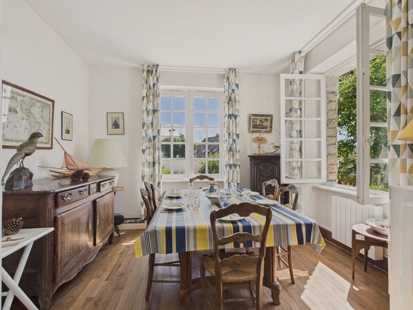 Comedor con mantel a rayas, sillas de madera y vistas a plantas.