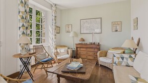 A cozy living room with wicker furniture, a wooden coffee table, and a green lamp. - Sea view – house for 4 adults and 3 children (Bénodet)