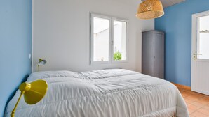 Una camera da letto con un letto, un armadio, una finestra e una lampada a sospensione.