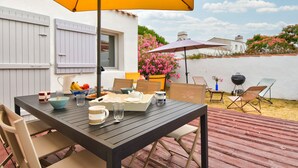 Patio esterno con tavolo da pranzo per quattro, circondato da sedie.