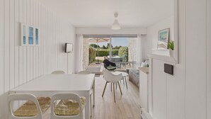 A modern, well-lit room with a dining area, a large window, and a view of the outdoors. - Sea-view apartment for 2 adults and 3 children (Carnac)