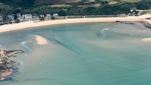 An aerial view of a coastal area with a sandy beach, clear water, and a cluster of houses in the background. - Sea-view apartment for 2 adults and 3 children (Carnac)