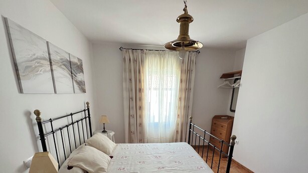 A bedroom with a bed, a nightstand, a chair, a wooden dresser, and a hanging light fixture. - Magnificent village house surrounded by nature. (Luque)