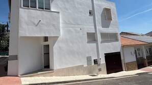 A modern two-story building with a flat roof, large windows, and a visible garage door. - Magnificent village house surrounded by nature. (Luque)