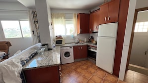 A compact kitchen with a washing machine, a microwave, and a refrigerator. - Magnificent village house surrounded by nature. (Luque)