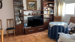 A living room with a TV, wooden shelves, a table, and chairs. - Magnificent village house surrounded by nature. (Luque)