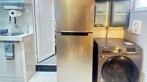 A compact kitchen with a stainless steel refrigerator, a washing machine, and a sink with a towel rack. - Whole place near Parque Kennedy (Miraflores)