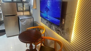 A modern kitchen with a built-in TV, a small dining area with a wooden table and chairs, and a decorative shelf with items. - Whole place near Parque Kennedy (Miraflores)