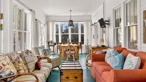 A cozy living room with a wooden floor, striped sofa, and a red couch.