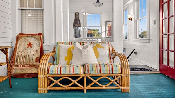 A room with a wicker sofa, a vintage Coca-Cola sign, and a large window with a view.