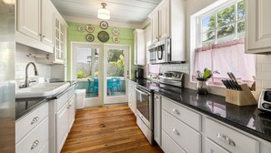 Una cocina con gabinetes blancos, un horno de acero inoxidable y una ventana con vistas al exterior.