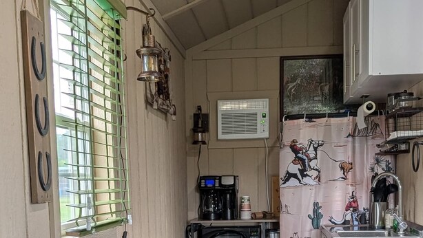 A compact kitchen with a microwave, coffee maker, and a sink. There are wooden stools and a small table. - Cozy cabin in charming Trenton NC (Trenton)