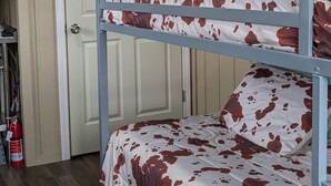 A bunk bed with a cow-print bedspread, a white door with a no-naggin allowed sign, and a horse silhouette decoration. - Cozy cabin in charming Trenton NC (Trenton)
