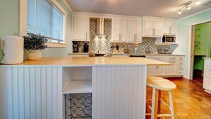 A kitchen with white cabinets, a wooden countertop, and a built-in microwave.
