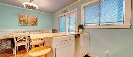 Una cocina con una isla de madera, armarios blancos y una ventana con persianas.