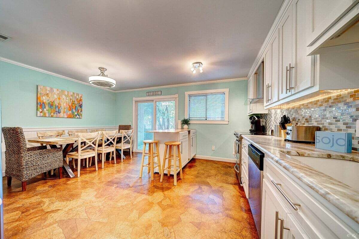 A kitchen with white cabinets, a marble countertop, and a dining area with a table and chairs.