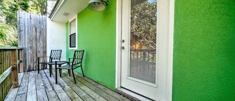 A wooden deck with a green wall and a white door with a window.