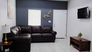A modern living room with a dark-colored sofa, a wooden coffee table, and a TV mounted on the wall.