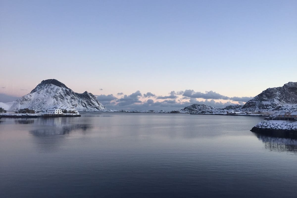 A serene lakeside view with snow-covered mountains and a calm water surface.
