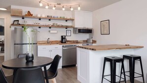Une cuisine moderne dotée d’un îlot central, d’appareils électroménagers intégrés et d’un coin repas avec des chaises noires.