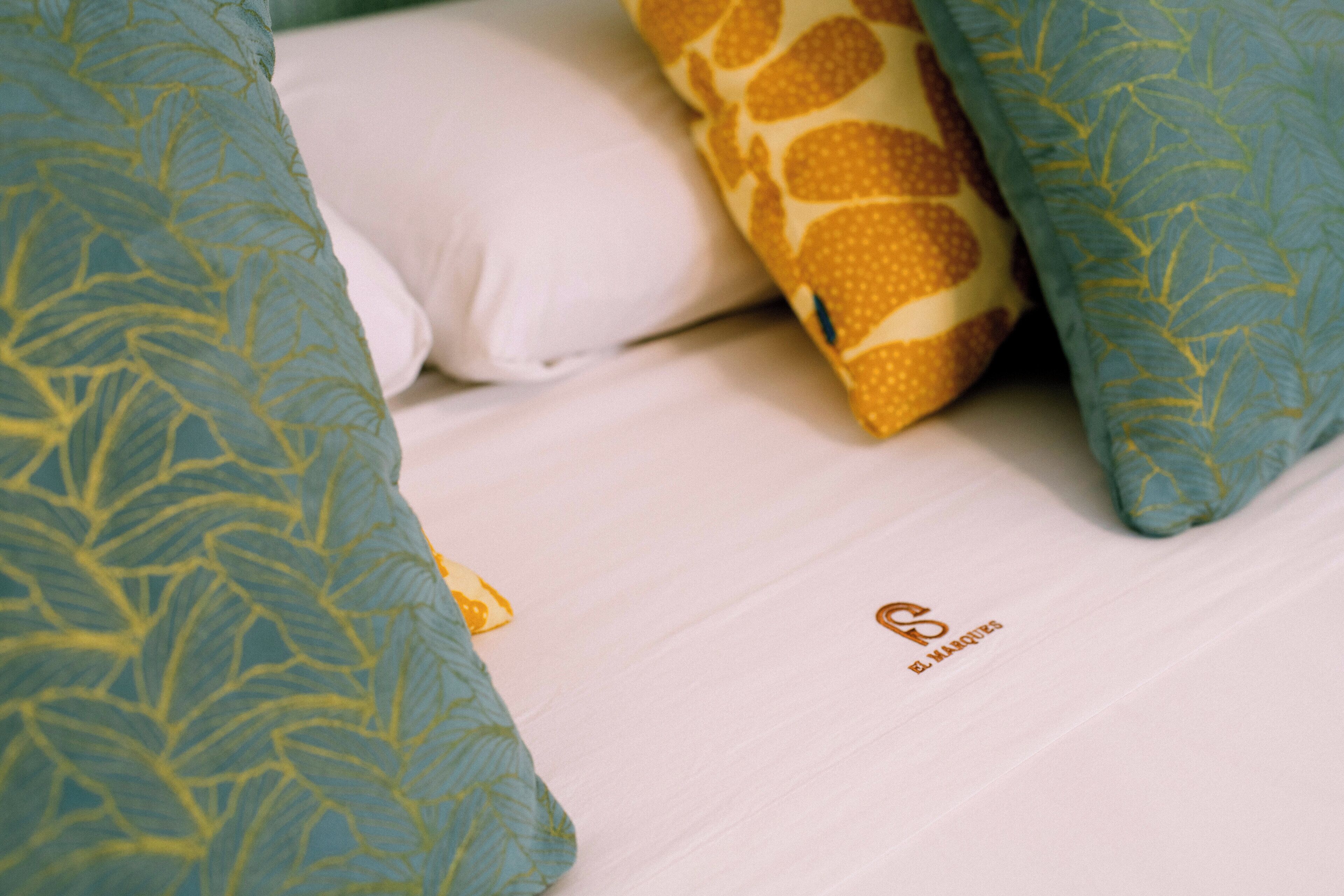 Un letto con cuscini decorati e un logo visibile sul materasso.