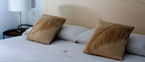 A bed with two pillows, a bedside lamp, and a nightstand.