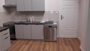 A compact kitchen with grey cabinets, a dishwasher, and a countertop with a sink and cleaning supplies. - Klimt2 – spacious 2-bedroom apt in Bielsko center, ideal for families & groups (Bielsko-Biała)