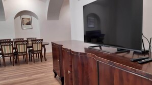 A dining area with a wooden table and chairs, a television on a stand, and a cabinet with a door. - Klimt2 – spacious 2-bedroom apt in Bielsko center, ideal for families & groups (Bielsko-Biała)