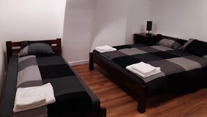 A bedroom with two beds, a nightstand with a lamp, and a wooden floor. - Klimt2 – spacious 2-bedroom apt in Bielsko center, ideal for families & groups (Bielsko-Biała)