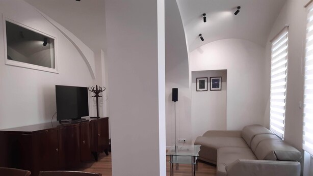 A living room with a dark wooden cabinet, a television, a glass coffee table, a beige sofa, and a dining area with chairs. - Klimt2 – spacious 2-bedroom apt in Bielsko center, ideal for families & groups (Bielsko-Biała)