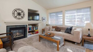 Una sala de estar con chimenea, televisor, sofá y mesa de centro.