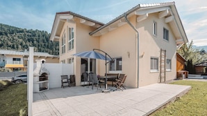 A two-story house with a patio, a barbecue grill, and a table with chairs. - Wonderful private villa for 10 guests with WIFI, TV, terrace and pets allowed (Zell Am See)