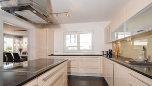 A modern kitchen with a black countertop, beige cabinets, and a window providing natural light. - Wonderful private villa for 10 guests with WIFI, TV, terrace and pets allowed (Zell Am See)