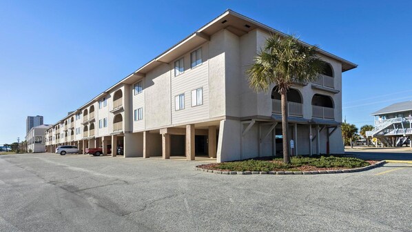 A multi-story hotel with a flat roof, large windows, and a central courtyard with a palm tree.