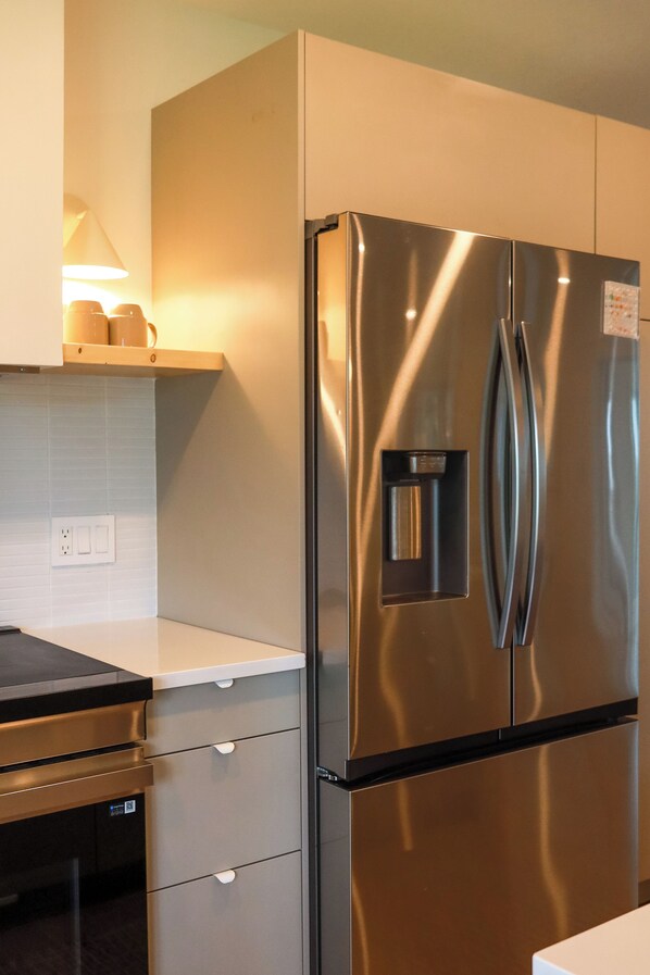 A stainless steel refrigerator with a water dispenser, a built-in oven, and a freezer compartment.