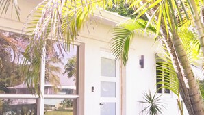 Una casa con fachada blanca, ventanas grandes y cimientos de ladrillo.